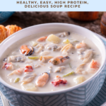 Seafood soup in a blue bowl with a creamy broth, shrimp, clams, and potato pieces, with text overlay reading “Seafood Soup, healthy easy high protein."