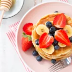 a flatlay of protein pancakes, fruit, and honey
