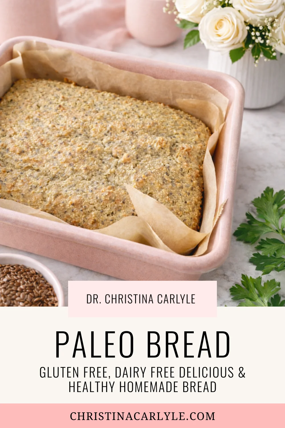 Paleo Bread This paleo bread recipe is gluten free, dairy free, and made with simple, wholesome ingredients. Soft on the inside with a lightly crisp, seed-speckled top, this healthy homemade bread is perfect for breakfast, toast, or sandwiches. Paleo bread baked in a light pink ceramic dish on a white marble countertop, topped with flax and chia seeds, styled with white roses and soft pink kitchen accents by Dr. Christina Carlyle.