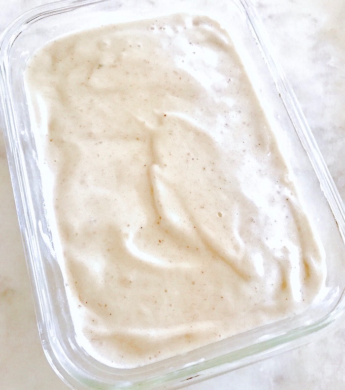 Blended frozen bananas and almond milk in a glass container on a countertop