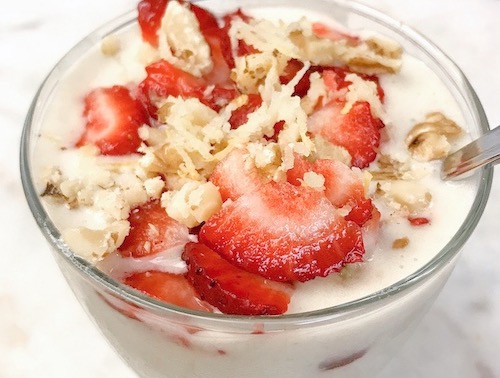a bowl of banana nice cream with fresh strawberries and lemon zest