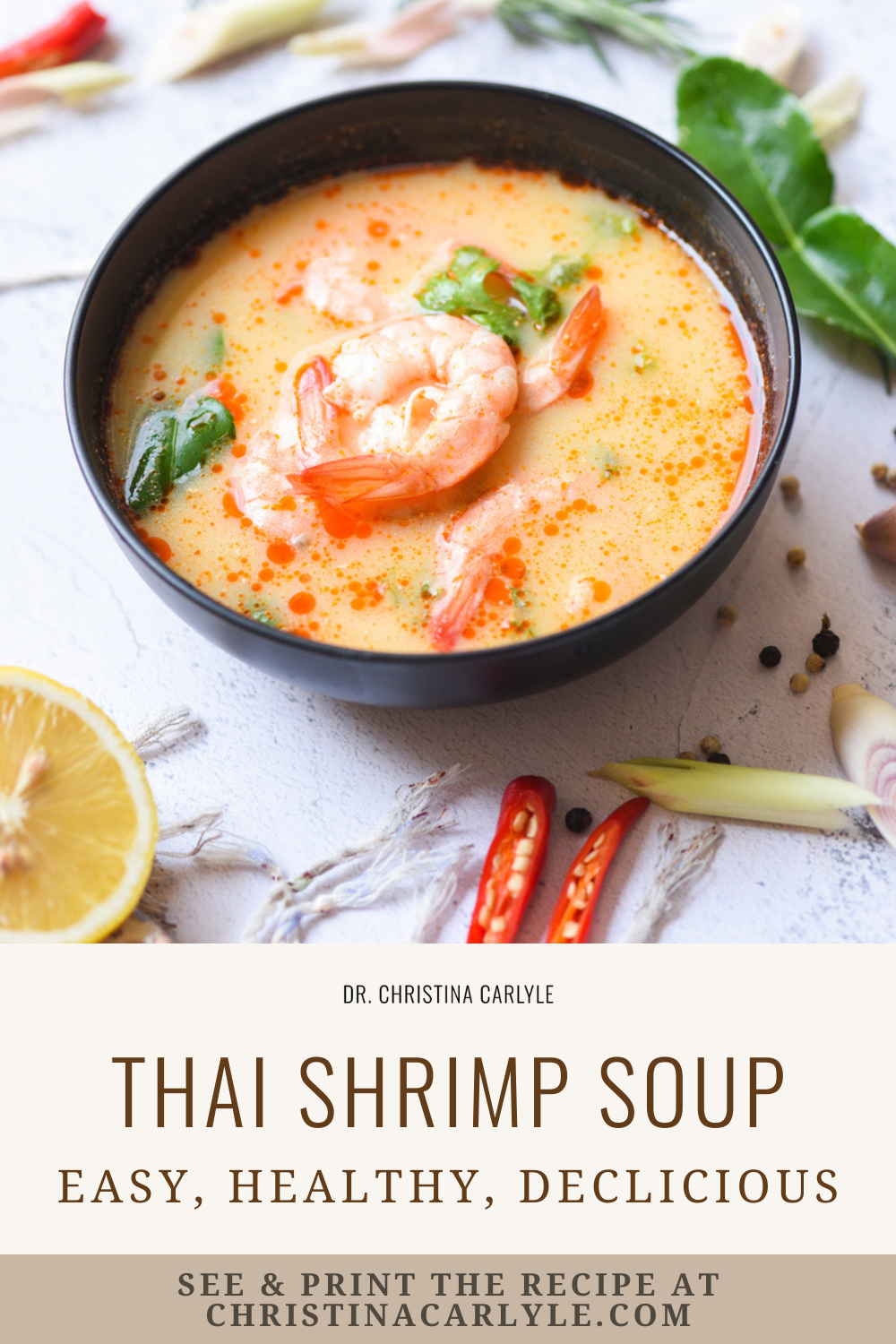 Thai shrimp soup in a black bowl with creamy coconut broth and shrimp, styled with lime, chili peppers, and herbs, with text overlay reading “Thai Shrimp Soup, easy, healthy, delicious.”