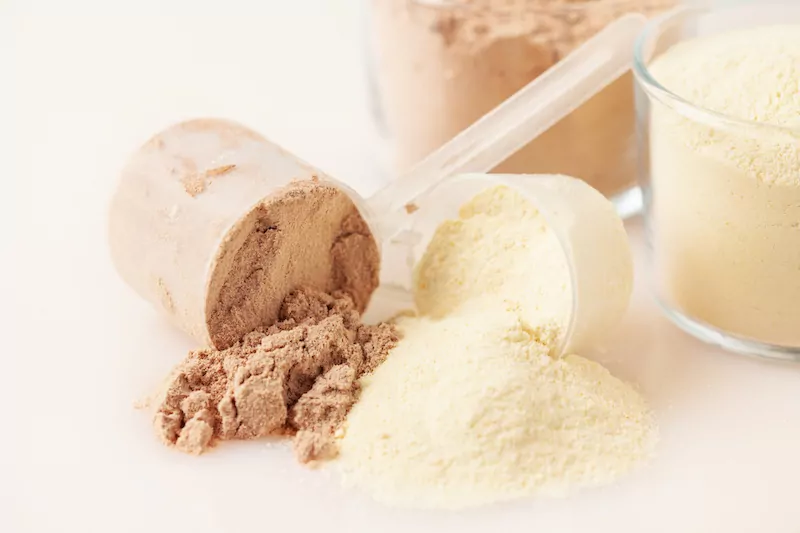 whey and soy protein powder on beige background