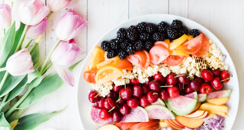 a fresh fruit plate and a bouquet of tulips on a table