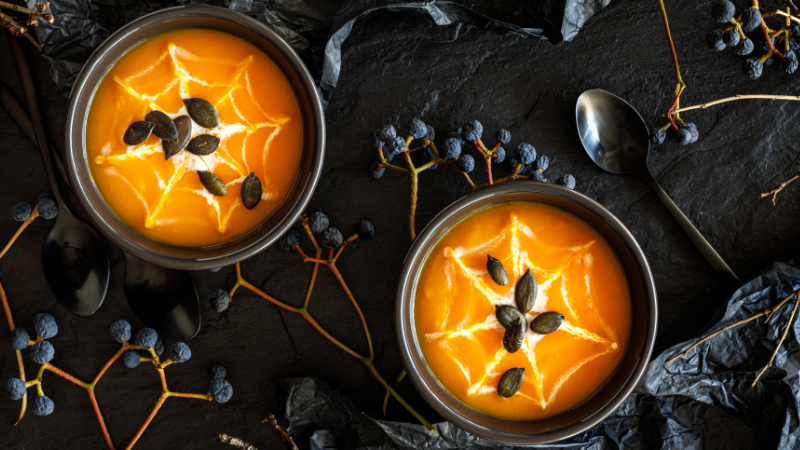 Pumpkin soup with spiderwebs made out of cream for Halloween dinner 