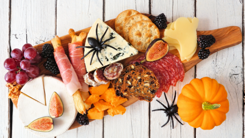 Charcuterie board with pumpkins and fake spiders Halloween Food Idea