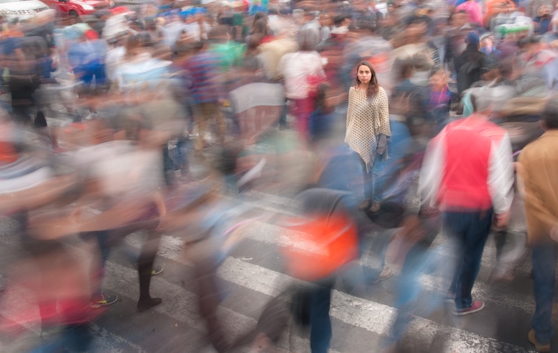a woman being isolated in a crowd of dozens of people that are out of focus to illustrate her unique bioindividuality