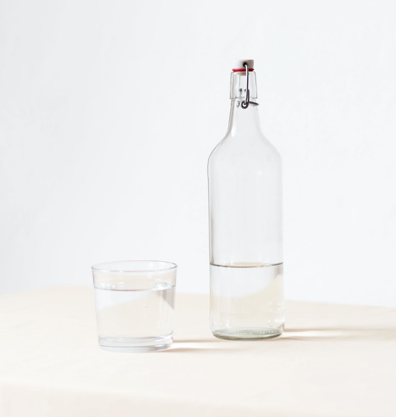 a glass of water and a water bottle on a countertop