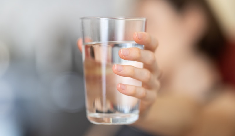 a woman holding out a glass of water