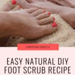 Close-up of feet with red toenails covered in sand, representing exfoliation for soft skin. Text overlay reads ‘Easy Natural DIY Foot Scrub Recipe for Soft Feet’ by Christina Carlyle