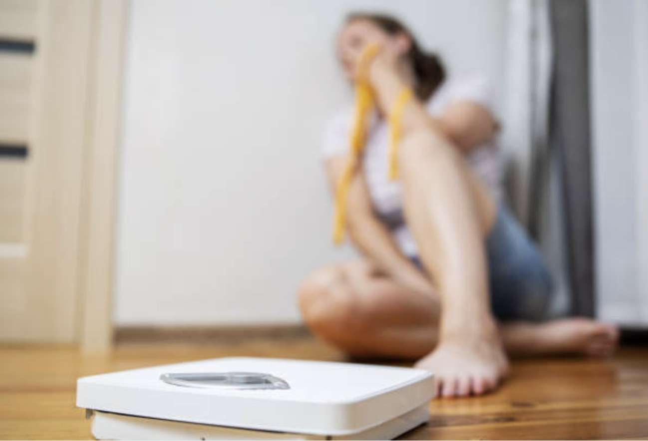 a woman looking sad next to a scale