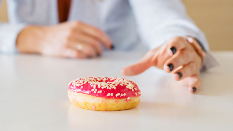 a picture of a woman's hand reaching for a donut