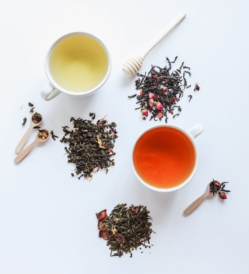 Herbal leaf dried tea and cups with drink, top view on white background
