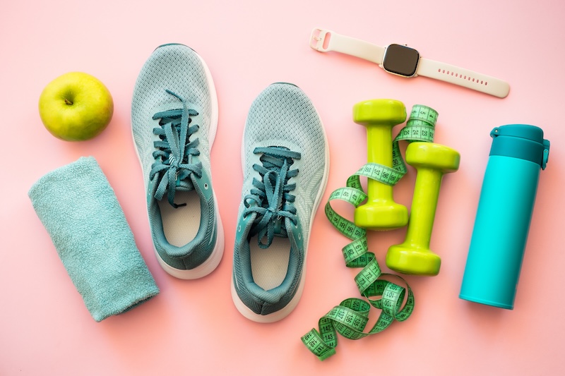 a flatlay of sneakers, workout equipment, a water bottle, and apple