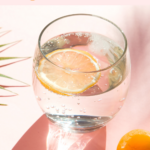 a glass of water with a lemon slice and backdrop with citrus and text that says 10 Best Clean Drinks
