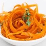 a bowl of carrot salad, carrot ribbons dressing in oil and herbs
