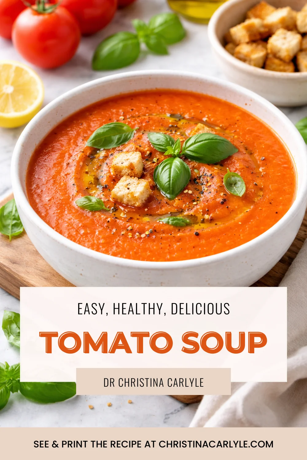 Tomato Soup Creamy tomato soup in a white bowl topped with basil and croutons, with text overlay reading “Easy, Healthy, Delicious Tomato Soup” and “Dr. Christina Carlyle.”