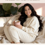 Dr. Christina Carlyle relaxing at home in cozy neutral loungewear while holding a warm mug on a sofa, demonstrating hygge inspired wellness and gentle at home fitness for healing metabolism, nervous system support, and sustainable health.