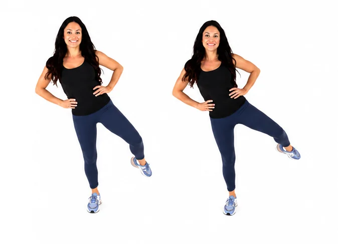 Dr. Christina Carlyle demonstrates standing hip dip pulses with hands on hips, lifting one leg out to the side to target the outer thighs, hips, glutes, and core.